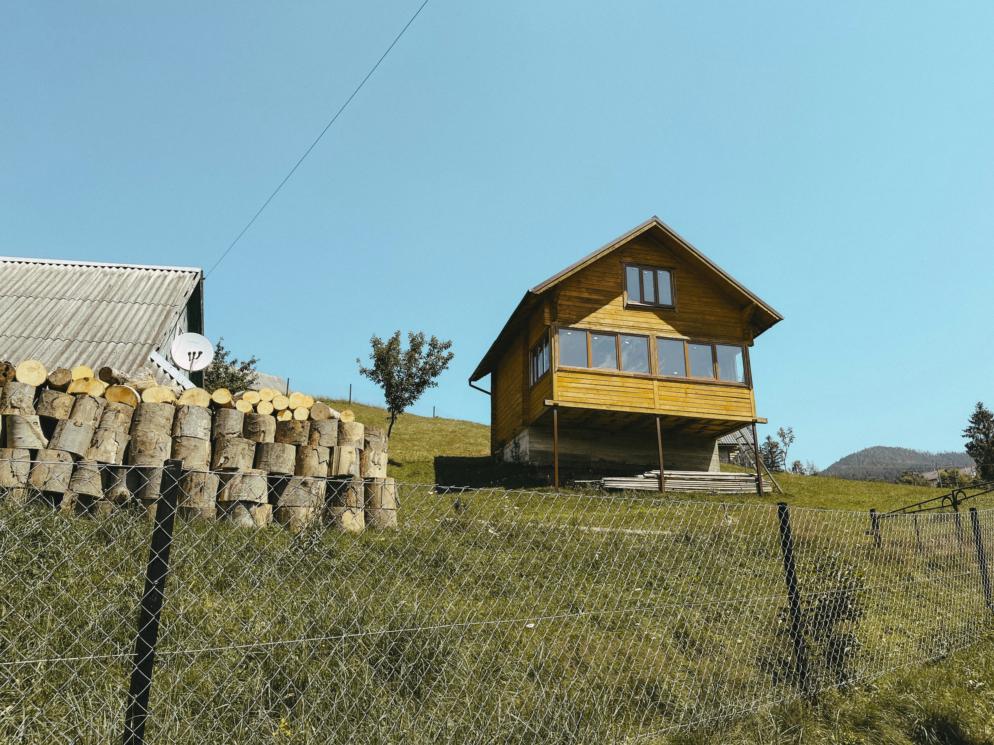 a wooden house sitting on top of a lush green hillside