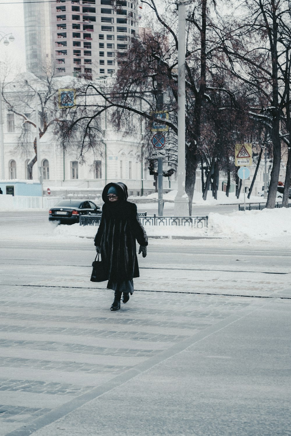 a woman walking down a street in the snow