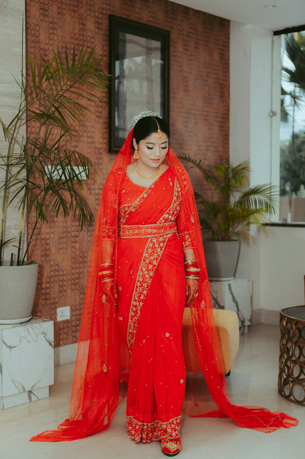 a woman in a red sari standing in front of a brick wall