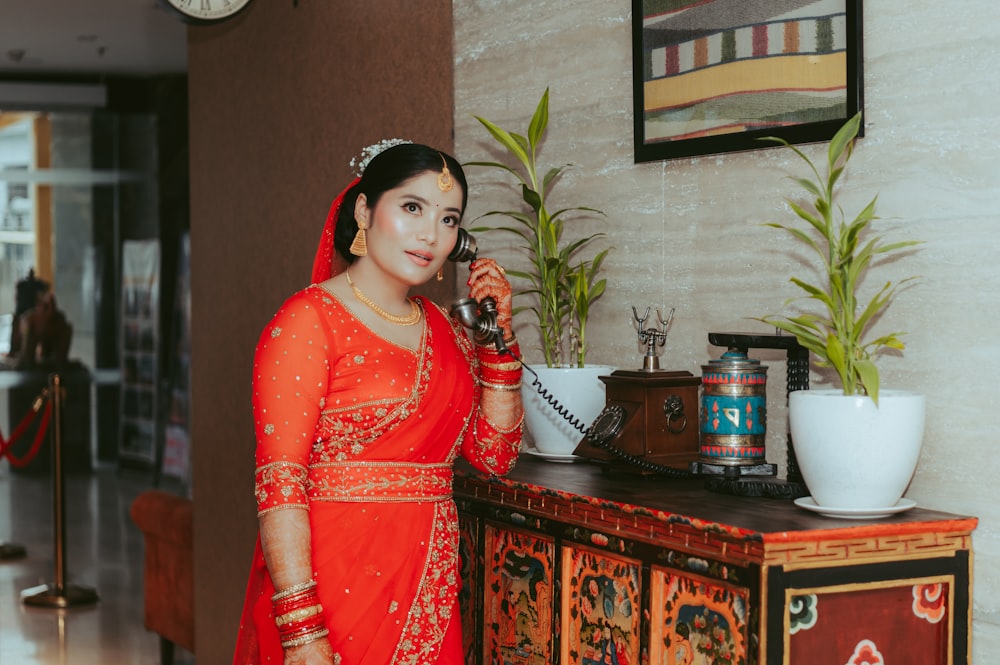 a woman in a red sari talking on a phone