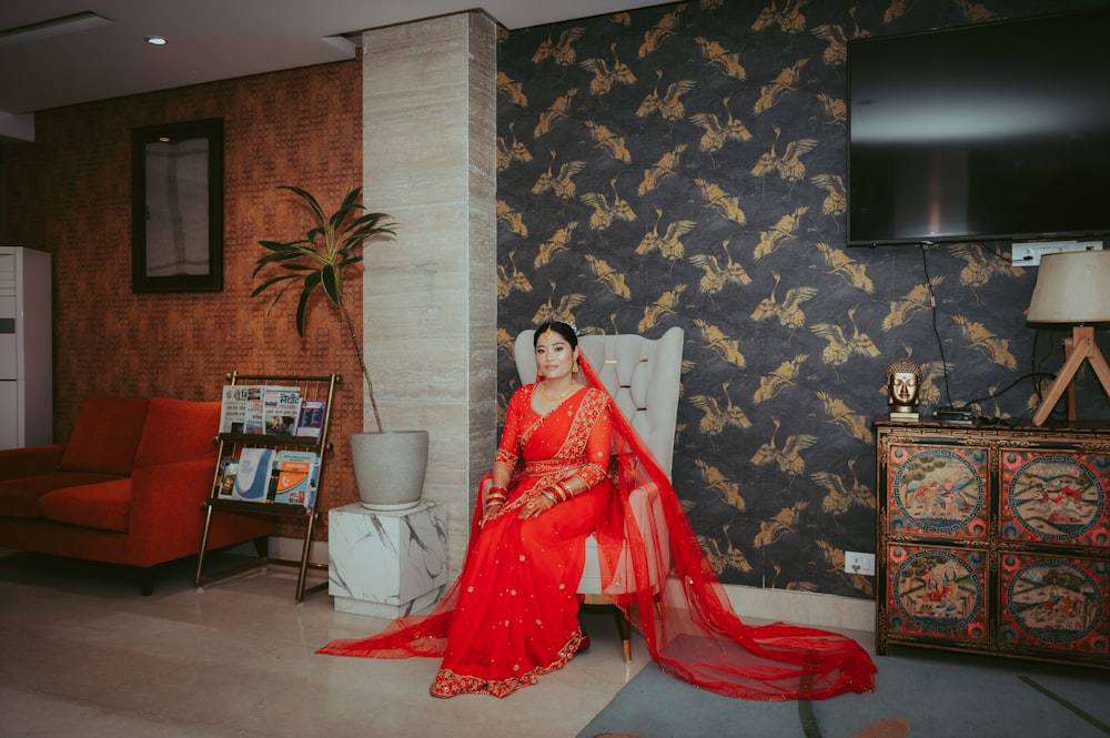 a woman in a red sari sitting on a chair