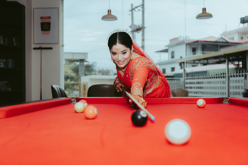 a woman in a red dress playing pool