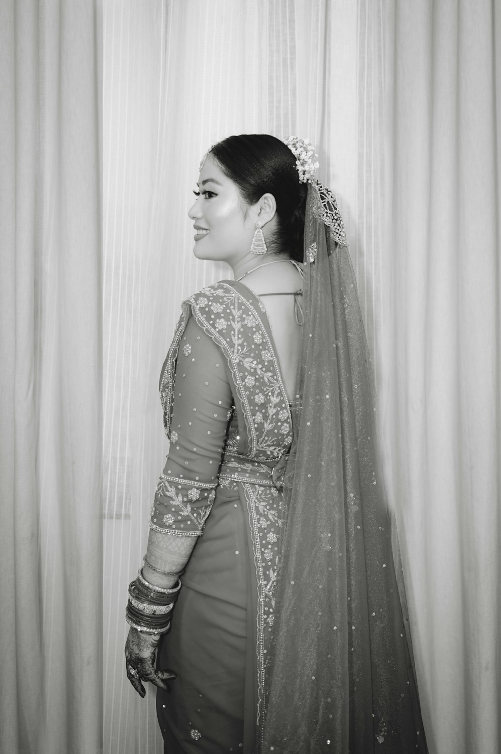 a woman in a bridal gown standing in front of a curtain