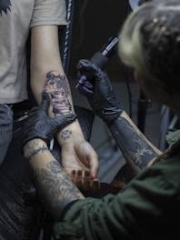 a person getting a tattoo on another person's arm