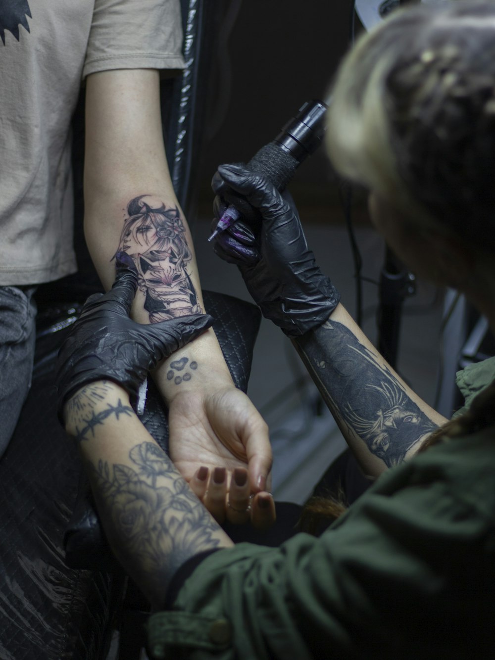 una persona che si fa tatuare il braccio di un'altra persona