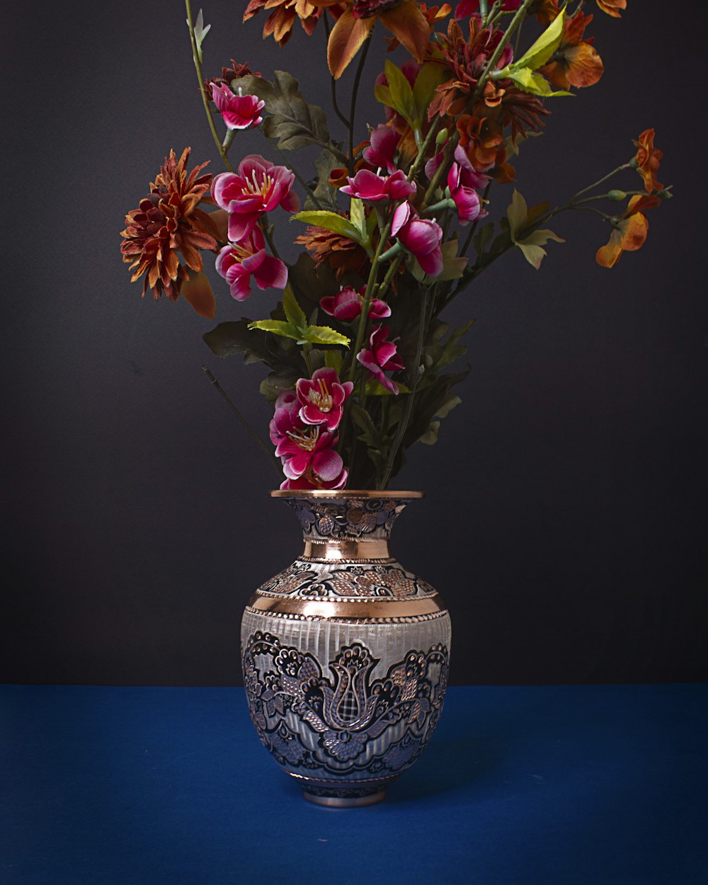 a vase filled with lots of flowers on top of a blue table