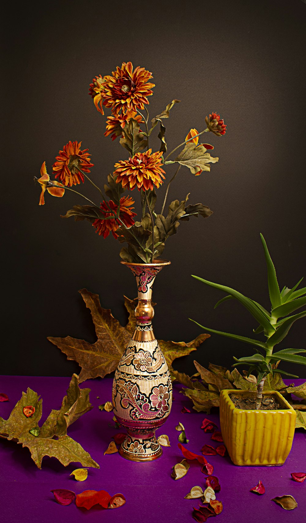 a vase filled with flowers next to a potted plant