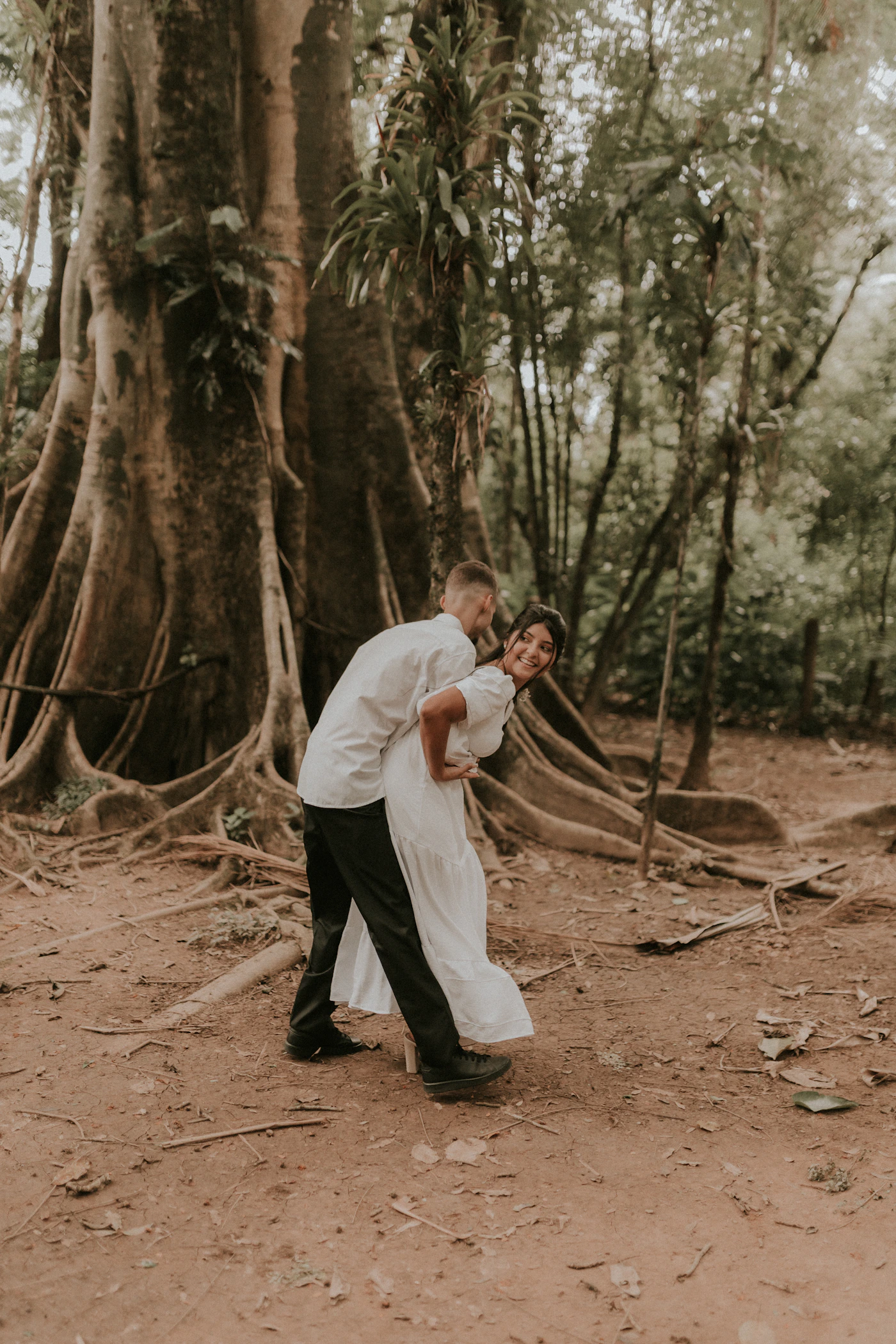 Couple in cloud forest elopement attire standing on a trail with the morning mist creating depth in the vegetation layers around them