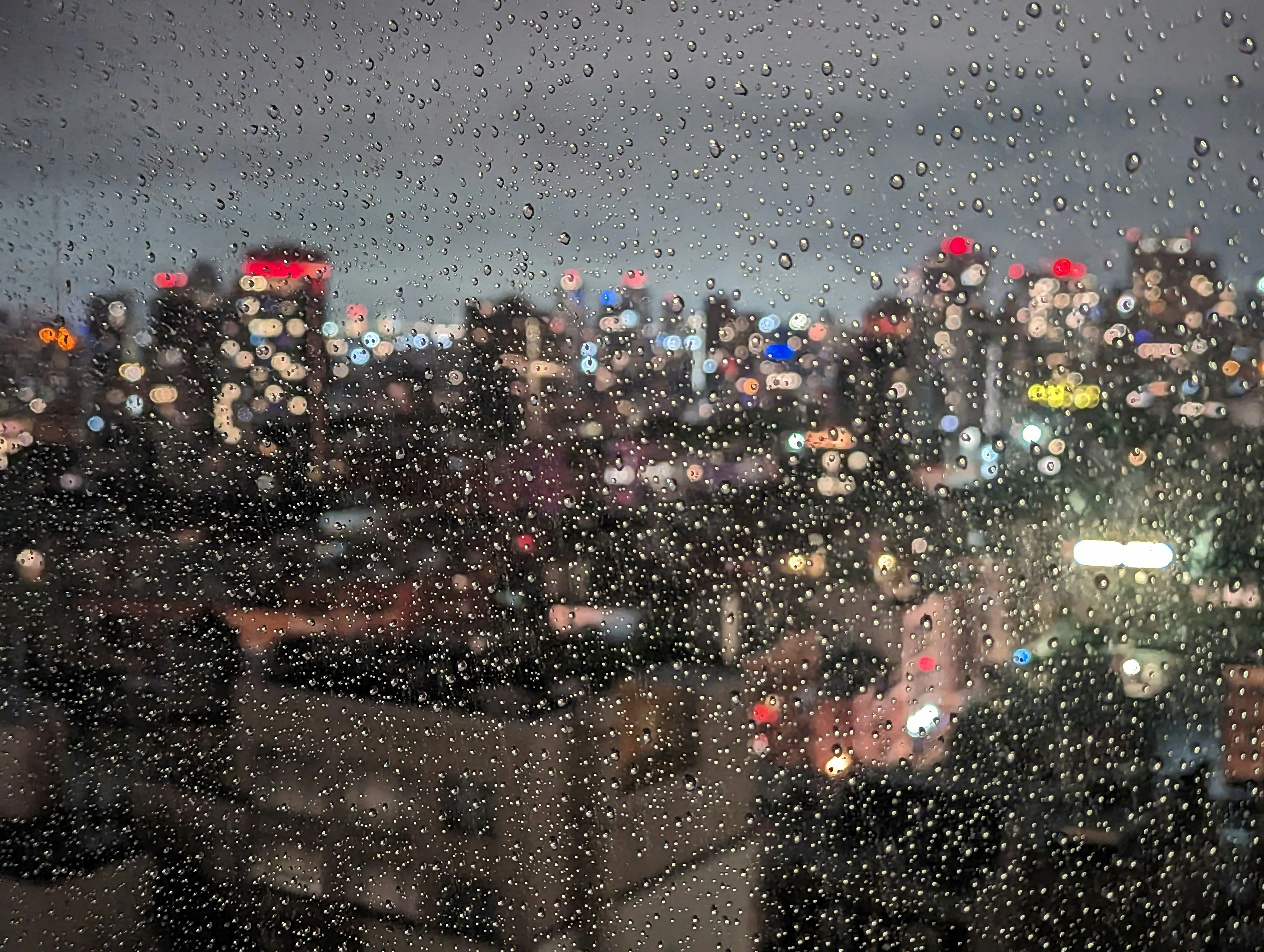 a view of a city at night through a rain covered window