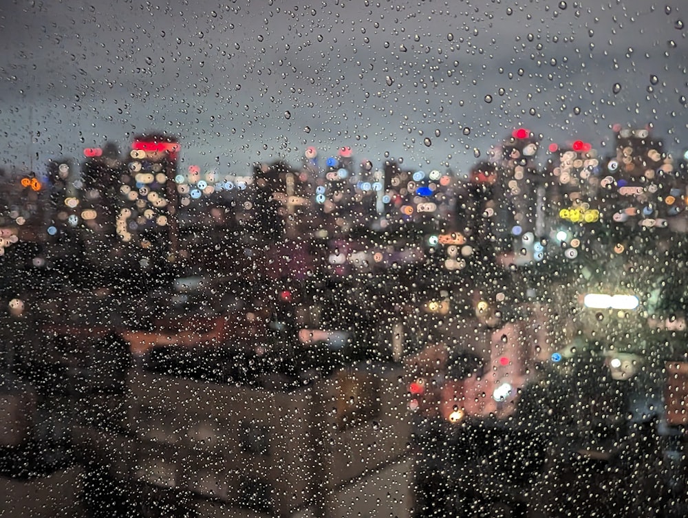uma vista de uma cidade à noite através de uma janela coberta de chuva