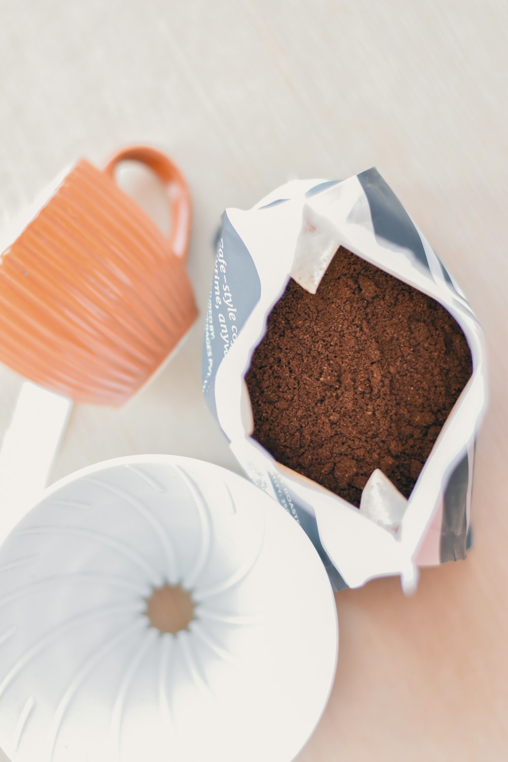 a cup of coffee next to a container of ground coffee