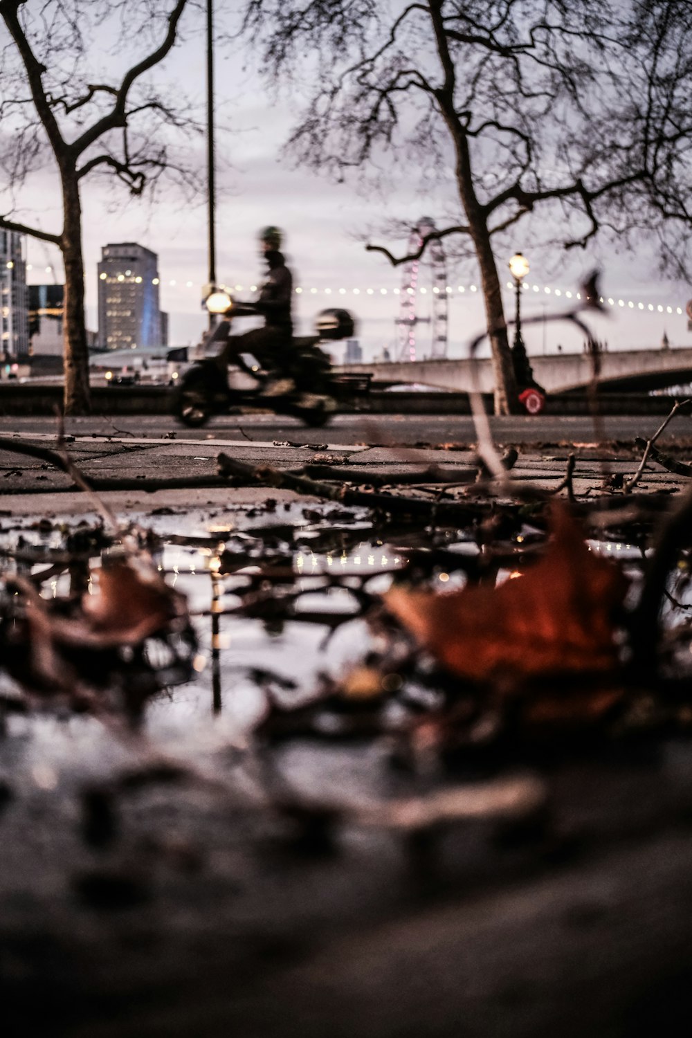 a man riding a skateboard down a street next to a puddle of water