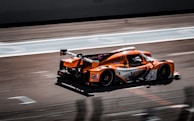 an orange race car driving down a race track