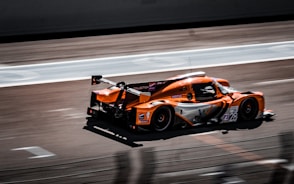 an orange raSuno AI v2 vs v3: A Comprehensive Comparisonce car driving down a race track