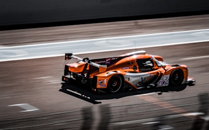 an orange raSuno AI v2 vs v3: A Comprehensive Comparisonce car driving down a race track