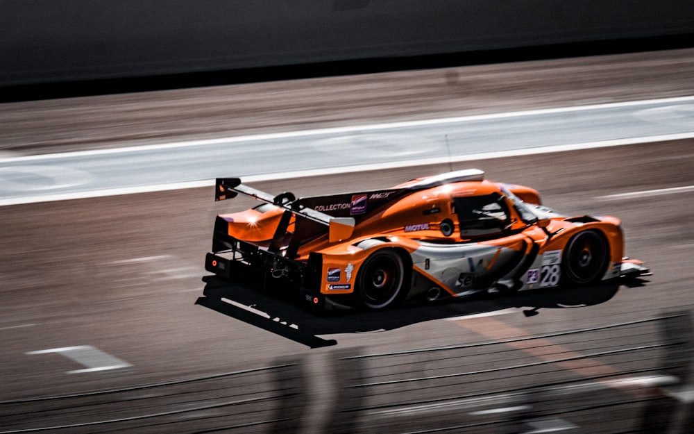 an orange race car driving down a race track