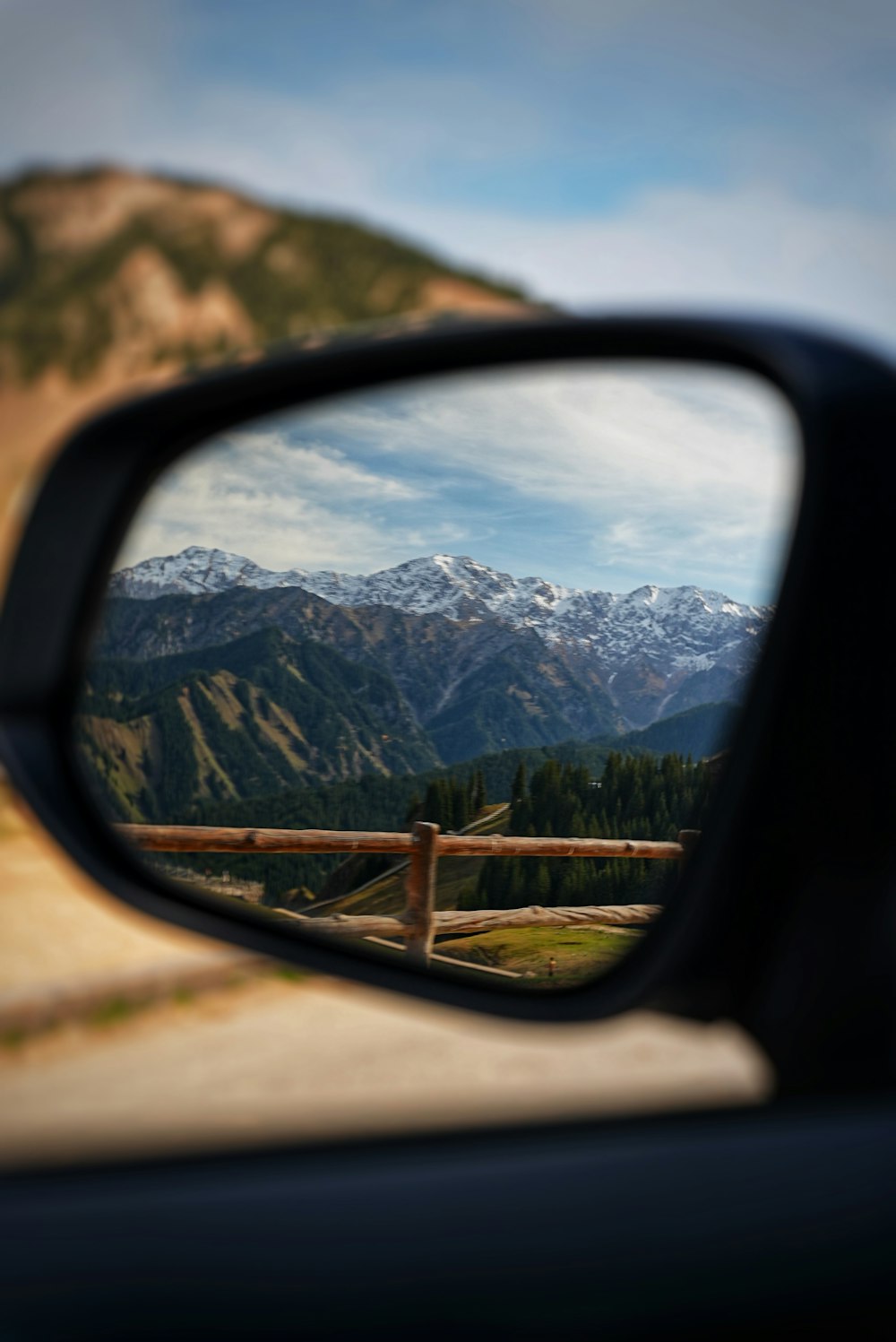 a car's side view mirror with mountains in the background