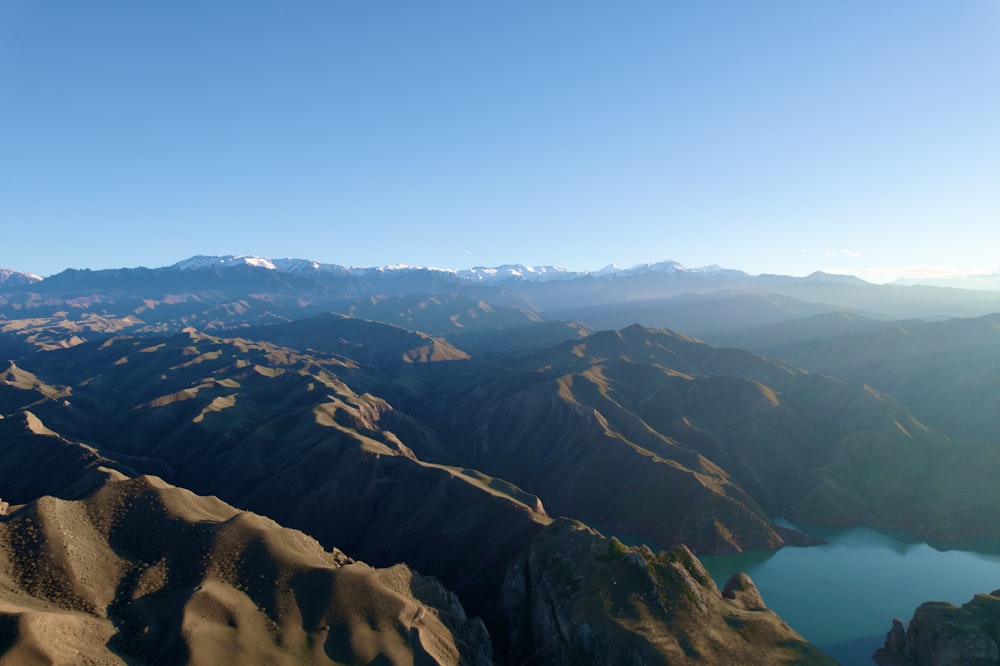 an aerial view of a mountain range with a lake in the foreground