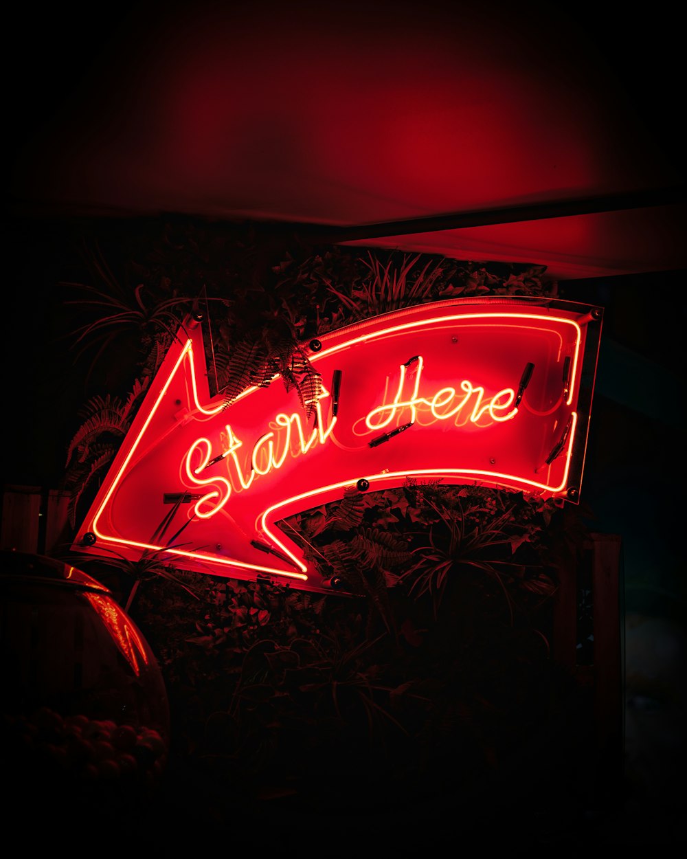 a red neon sign that says start here