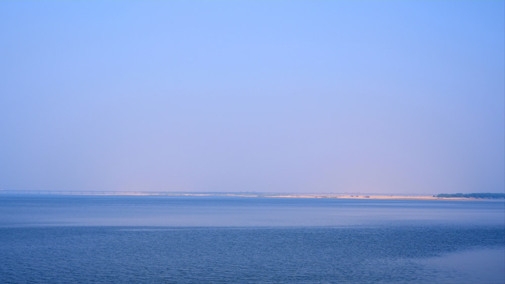 a large body of water sitting under a blue sky