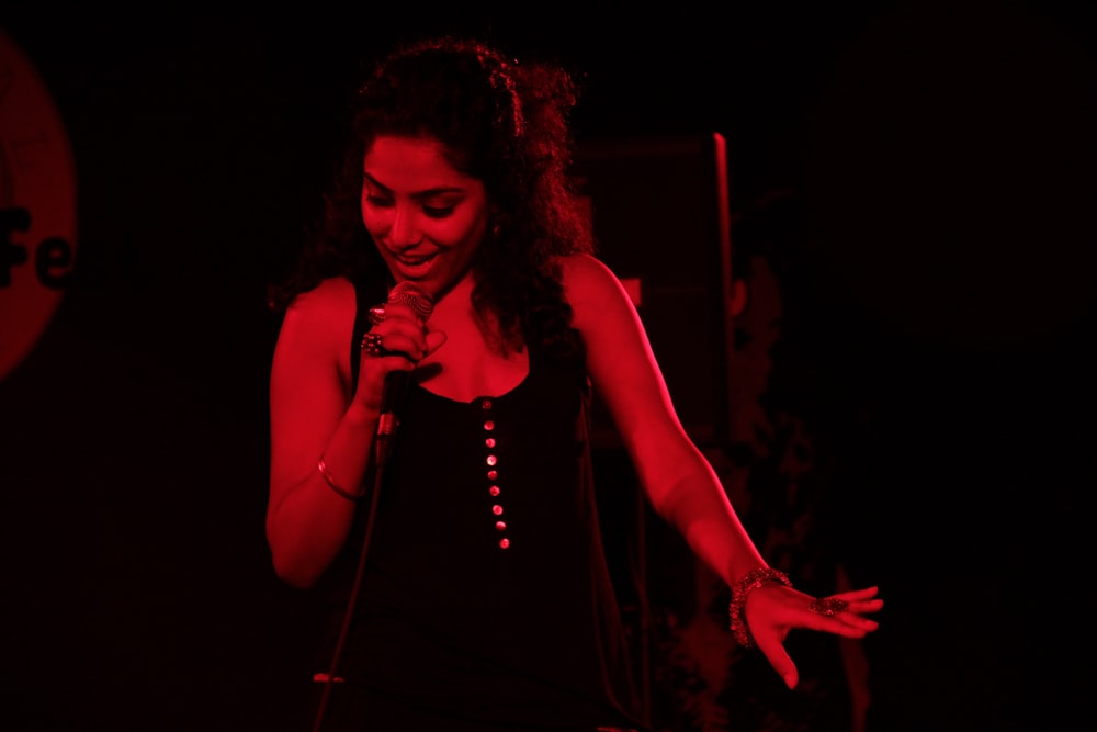 a woman singing into a microphone in a dark room