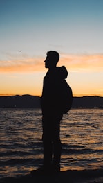 a man standing on a beach at sunset