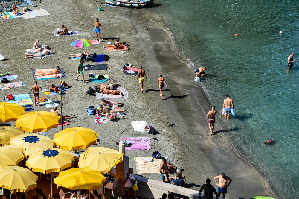 a group of people on a beach with yellow umbrellas