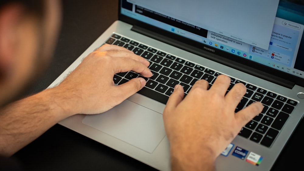 a man is typing on a laptop keyboard