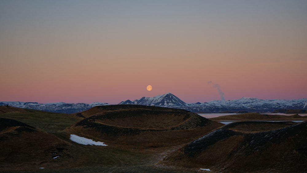 la luna se está poniendo sobre una cadena montañosa