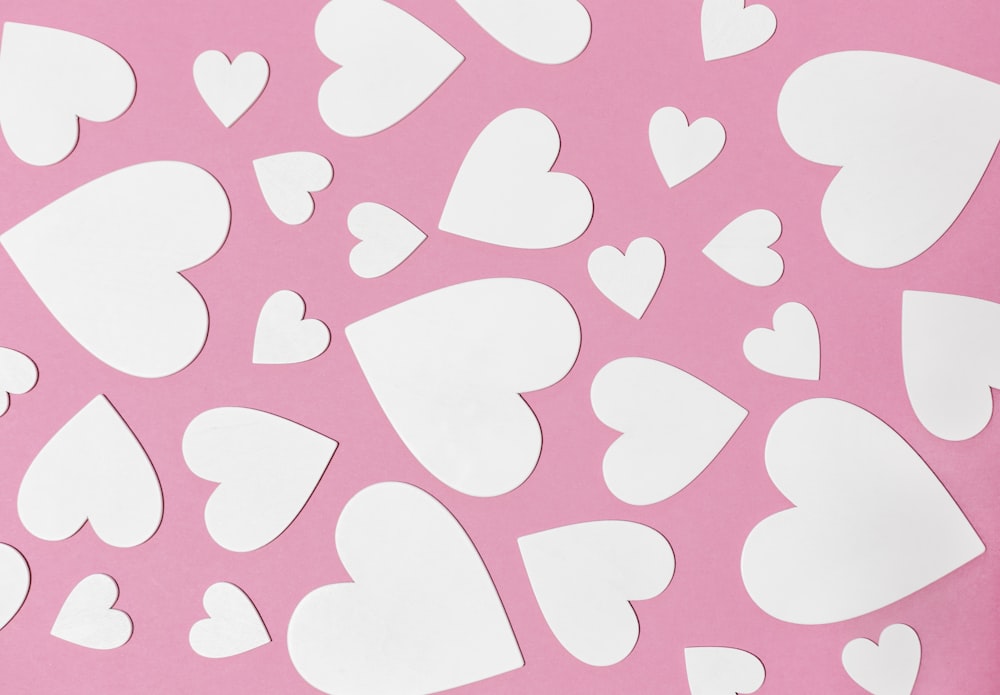 a bunch of cut out hearts on a pink background