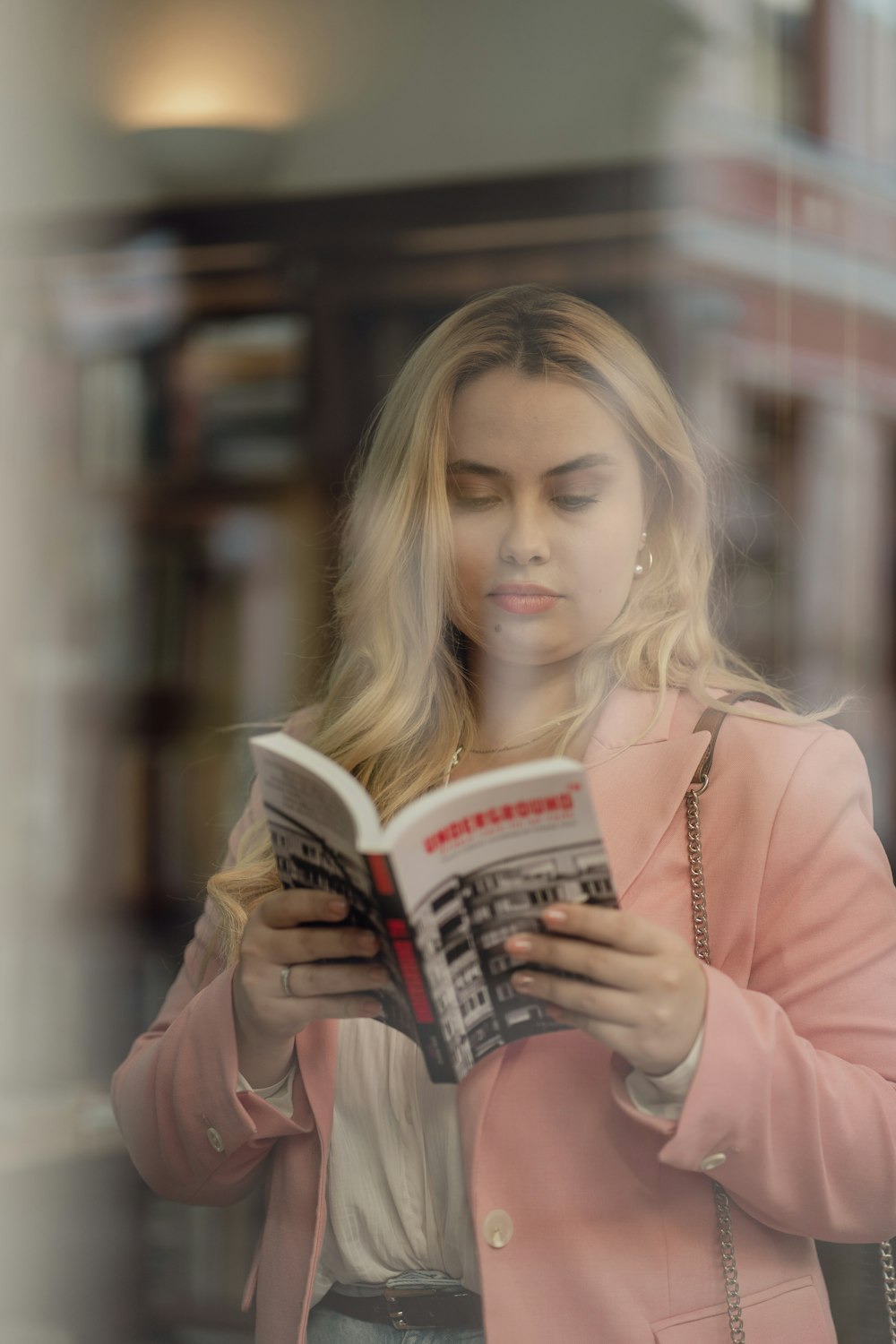a woman in a pink coat reading a book