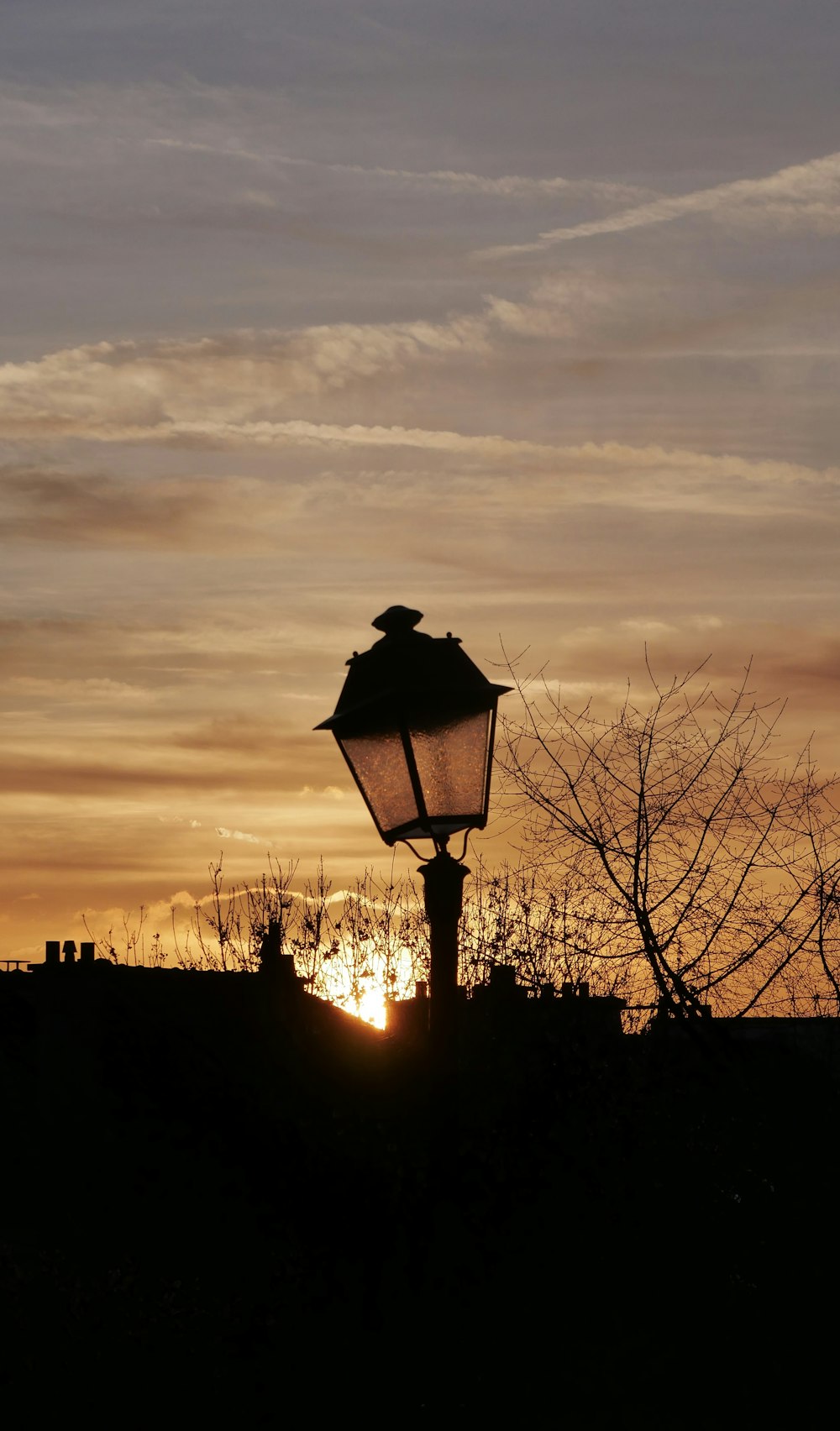 a street light with the sun setting in the background