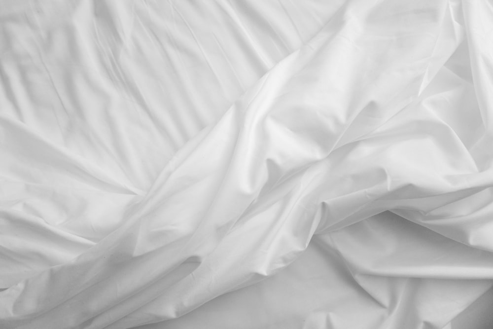 a black and white photo of a bed with white sheets