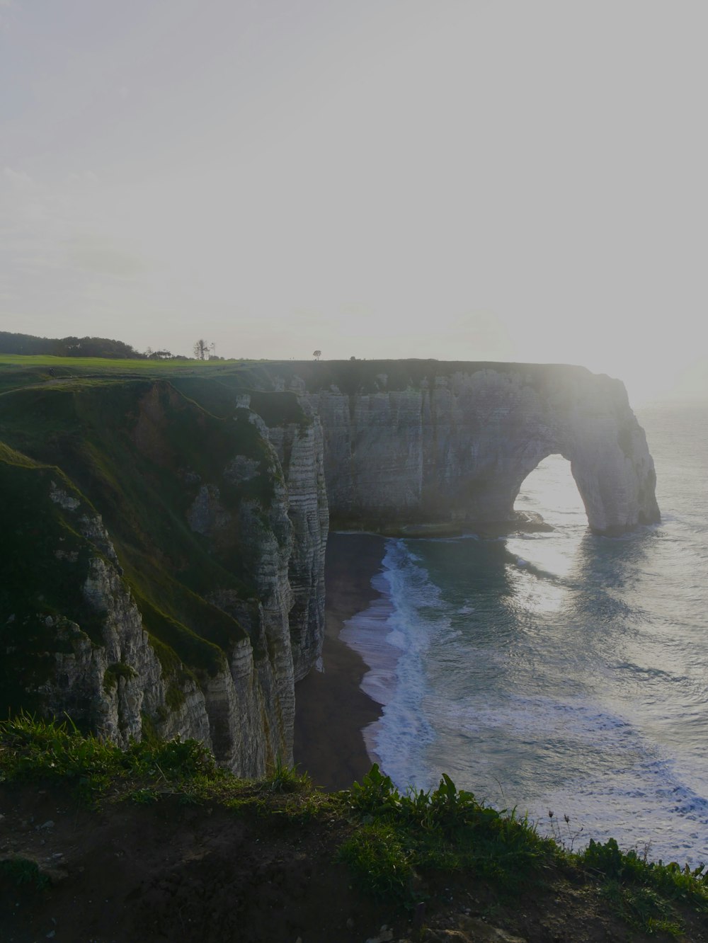 a large rock formation near the ocean on a sunny day