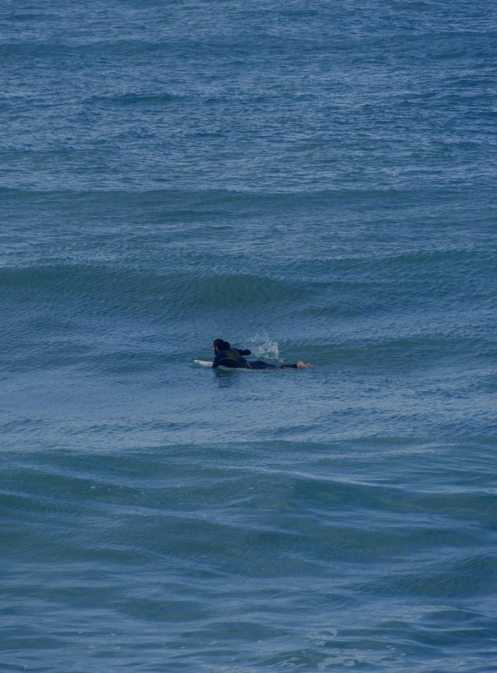 a person laying on a surfboard in the ocean