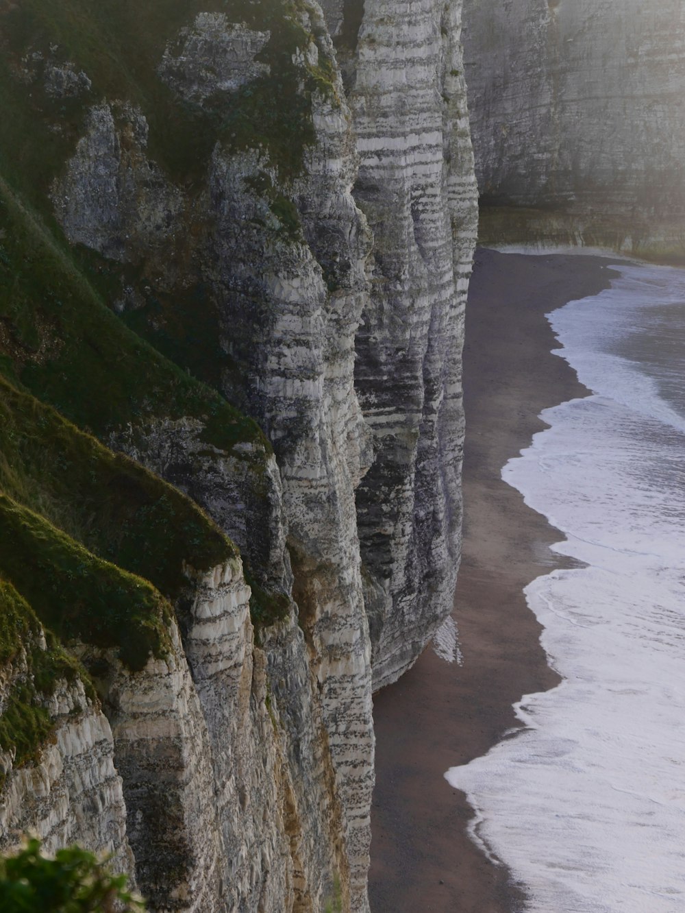 a view of a beach and cliffs from a high cliff