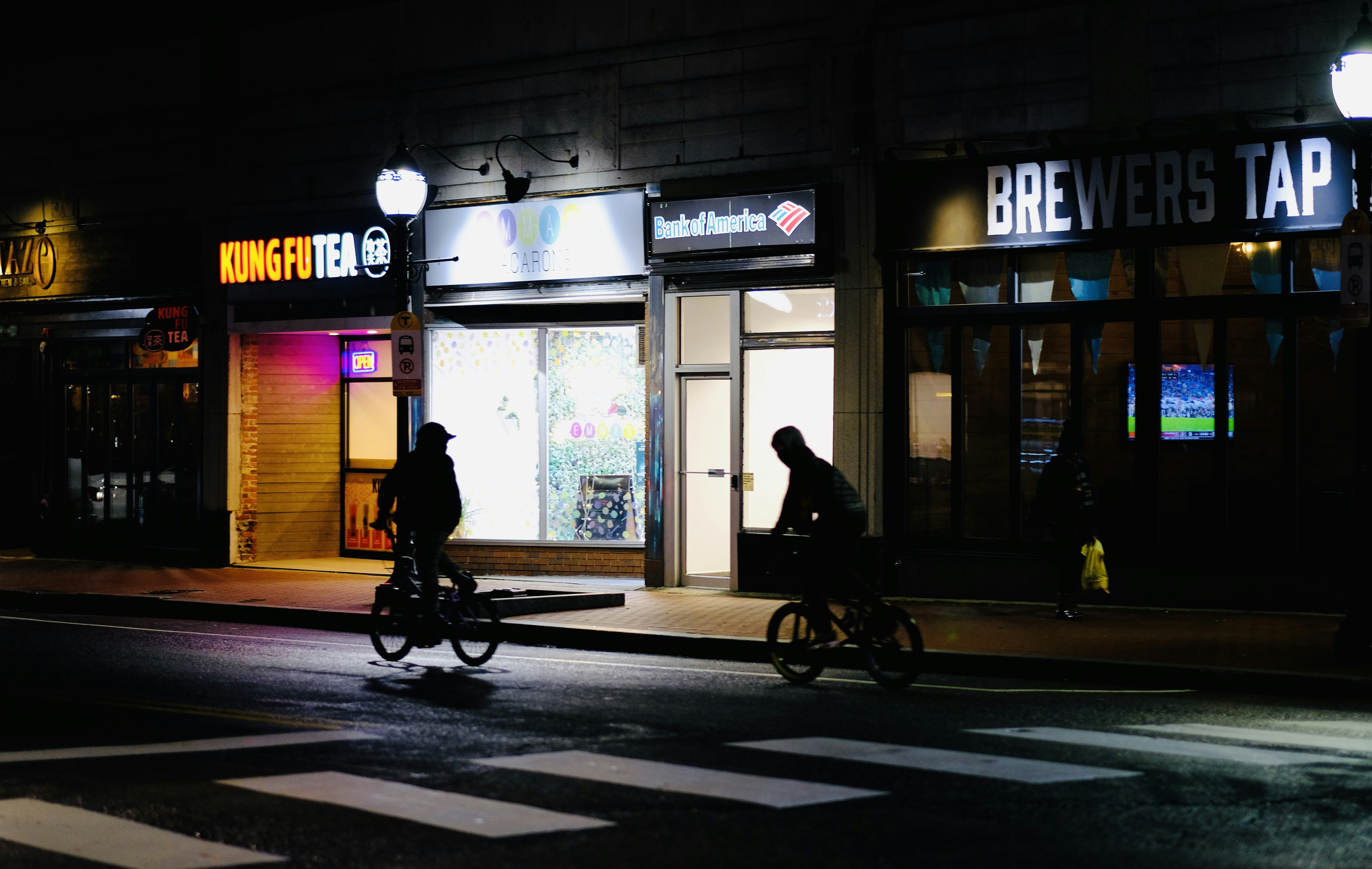 a couple of people riding bikes down a street at night