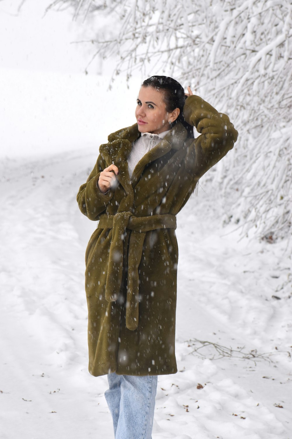 a woman standing in the snow wearing a coat
