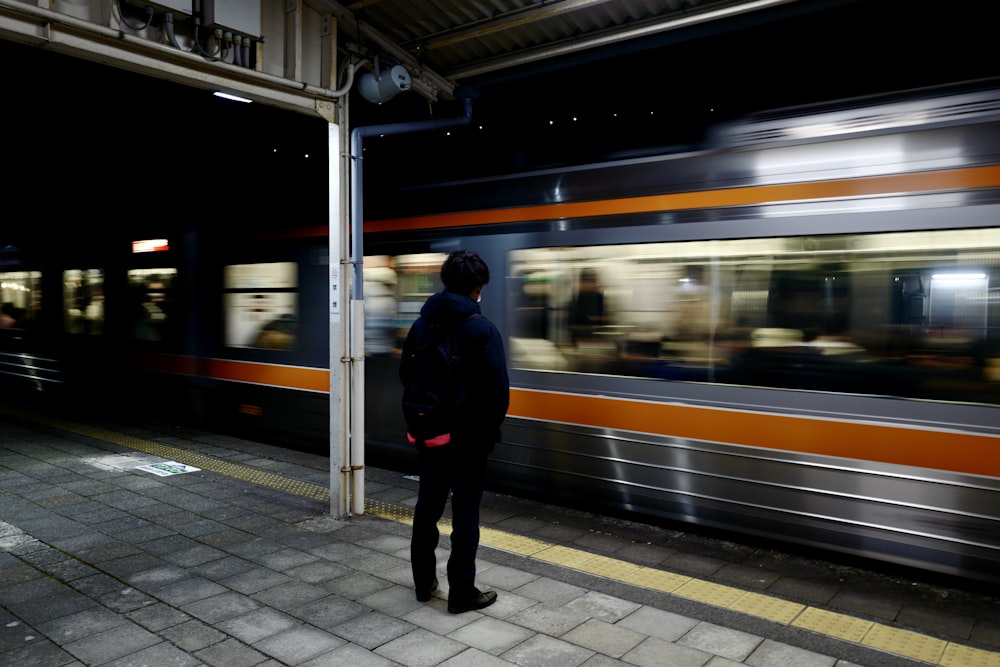 Un homme attend un train dans une gare