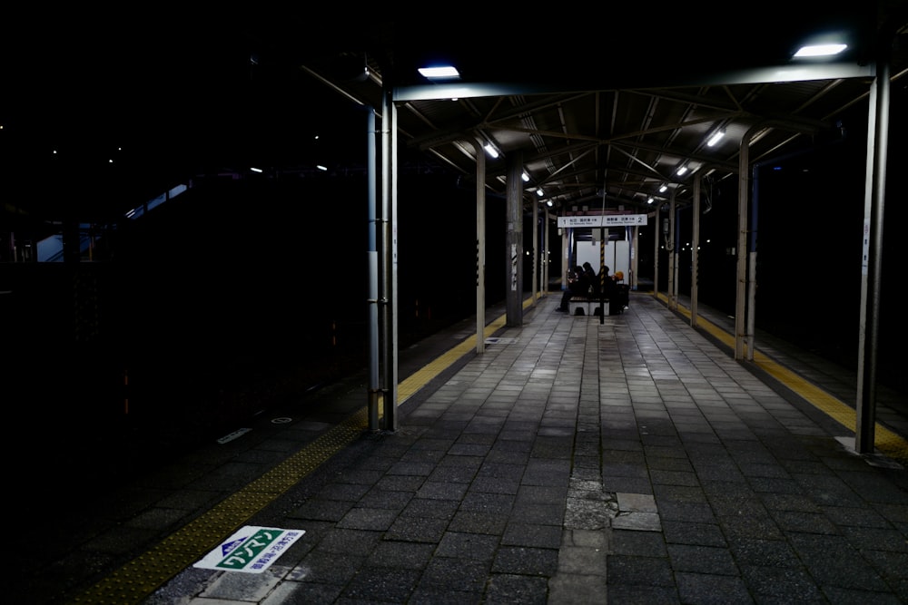 a train station with people sitting on benches at night