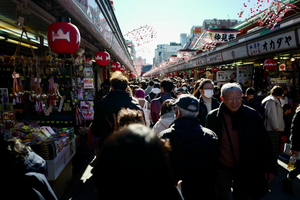 une foule de gens marchant dans une rue à côté de magasins