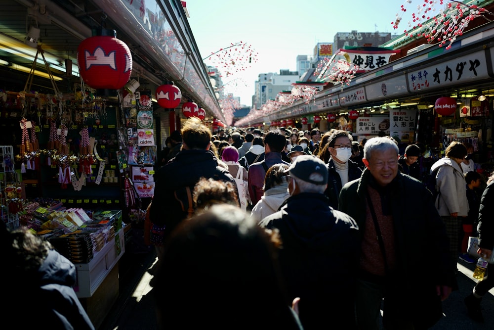 a crowd of people walking down a street next to shops