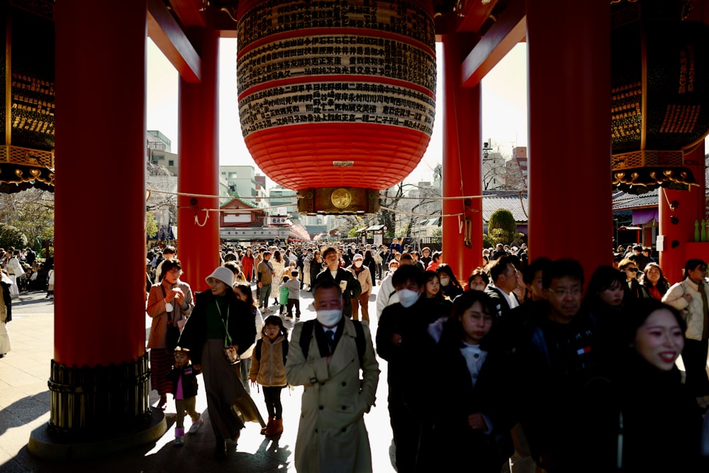 a group of people walking under a red structure