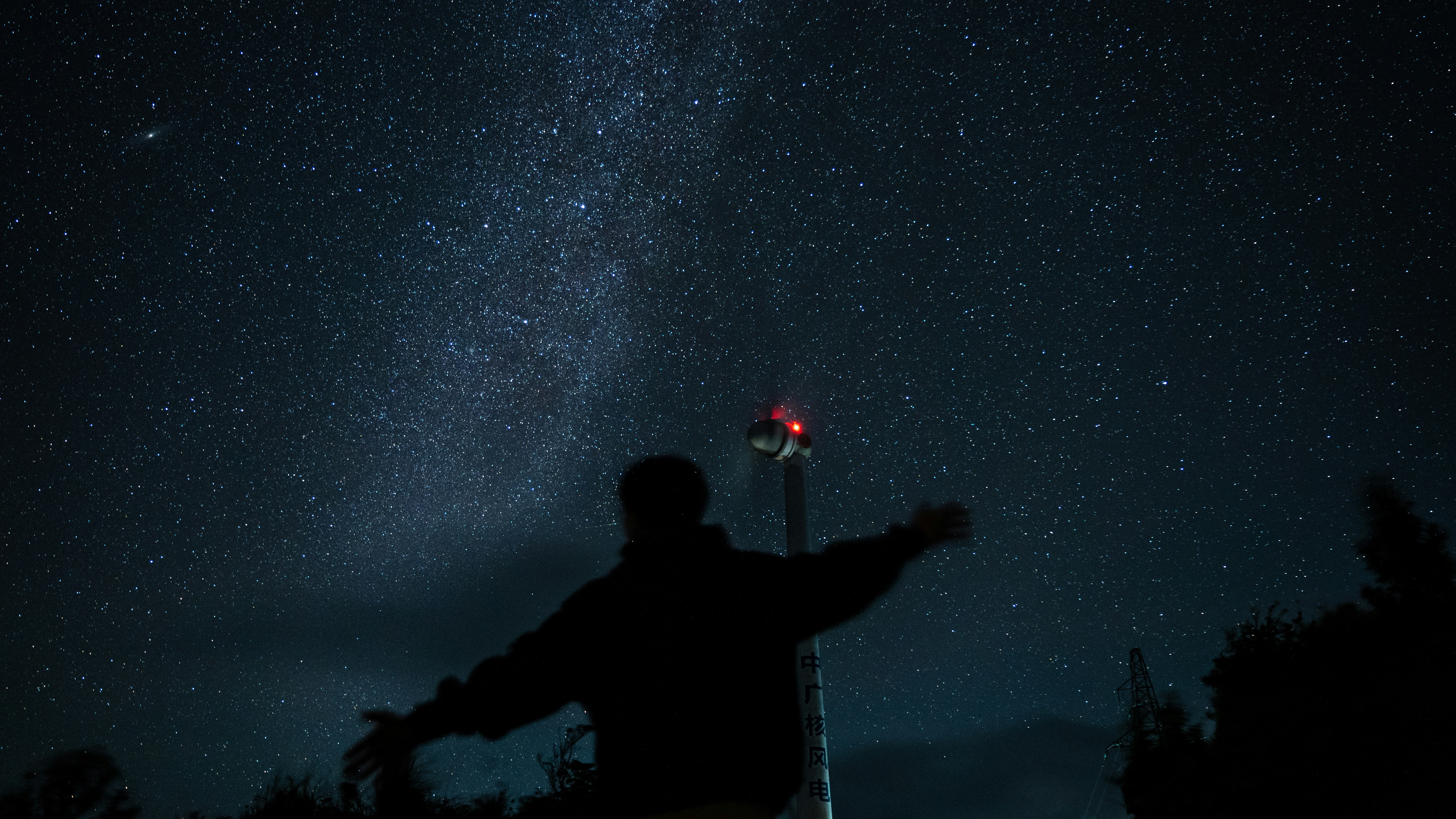 a man standing in front of a street light under a night sky filled with stars
