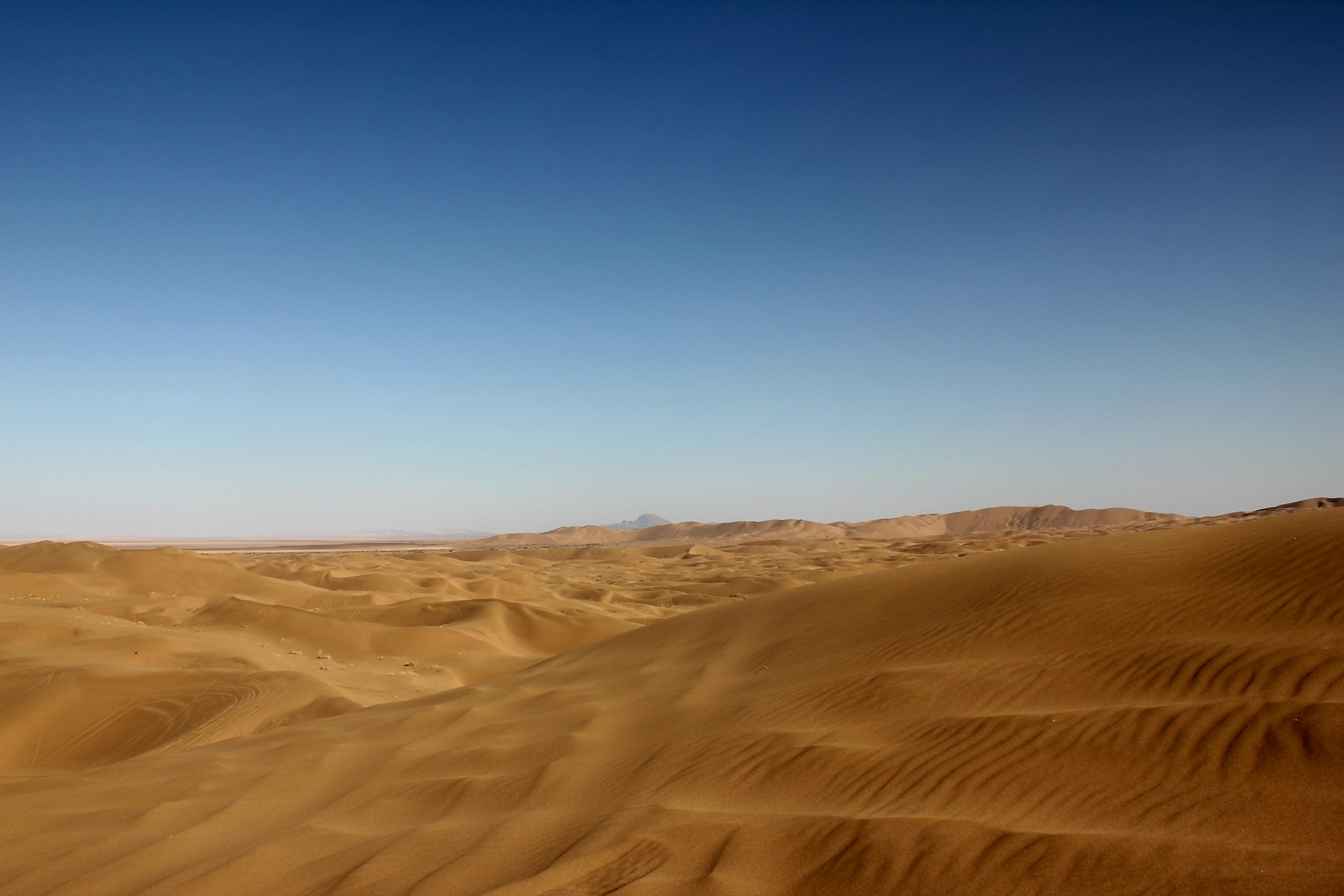 a desert landscape with sand dunes and mountains in the distance