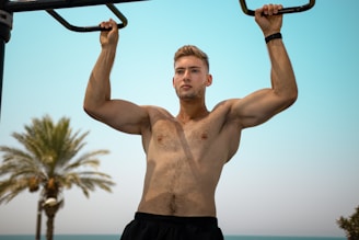 a shirtless man holding a bar in front of his face