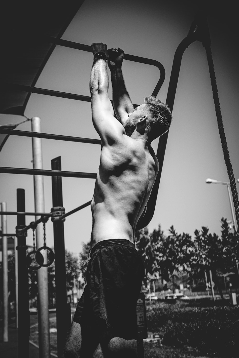 a shirtless man hanging upside down on a pull up bar