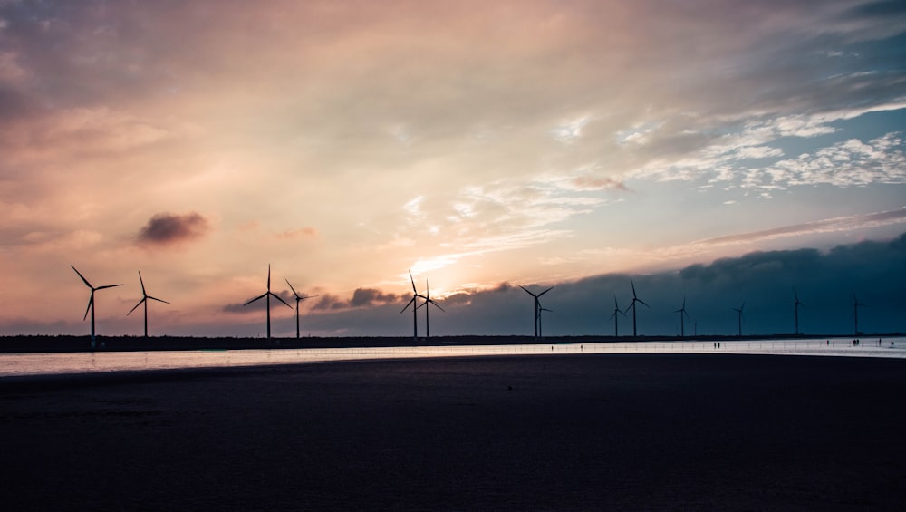 a group of windmills standing on top of a beach