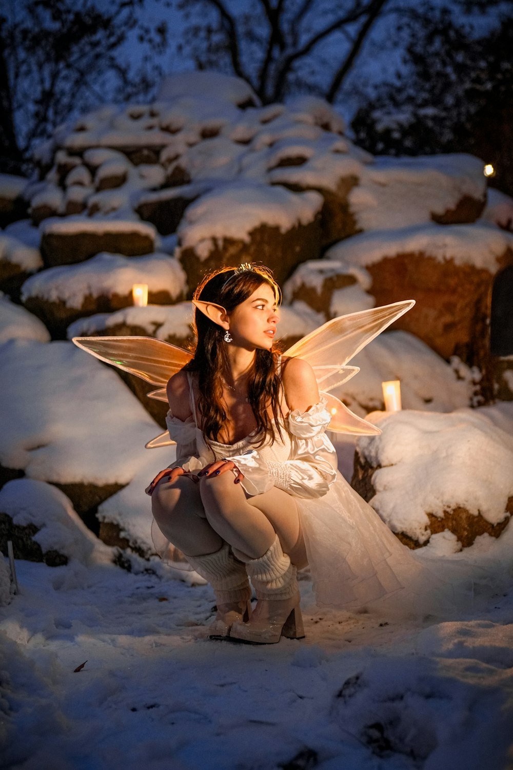 a woman dressed as a fairy kneeling in the snow