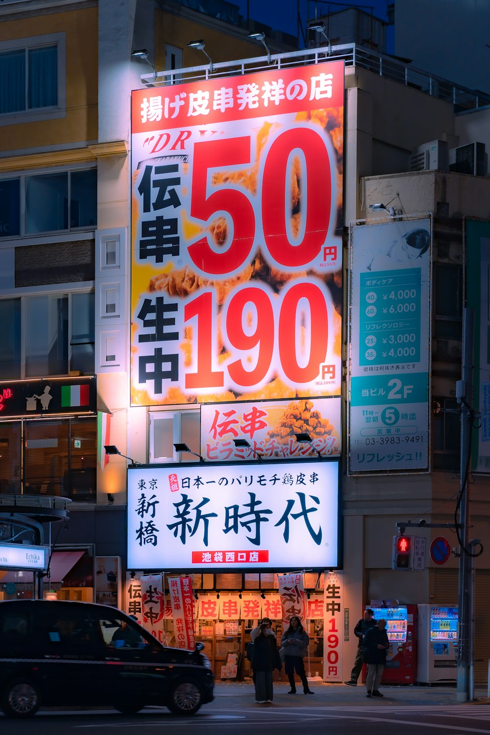 une rue de la ville la nuit avec une grande publicité sur le côté d’un bâtiment